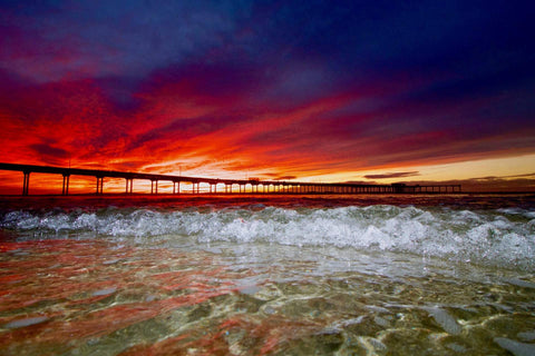 Sunset over a pier with vibrant red and orange colors in the sky.  Shot in San Diego, California. © Randy Dible Photo
