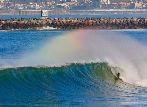 Surfer riding a wave with a rainbow in the background. Shot in San Diego, California. © Randy Dible Photo