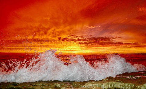 Sunset over the ocean with waves crashing against a rocky shore. Shot in San Diego, California. © Randy Dible Photo