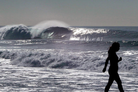 Person walking on a beach with large waves in the background. Shot in San Diego, California. © Randy Dible Photo