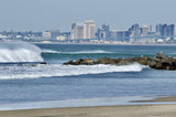 City skyline with waves crashing against rocks on a beach.  Shot in San Diego, California. © Randy Dible Photo