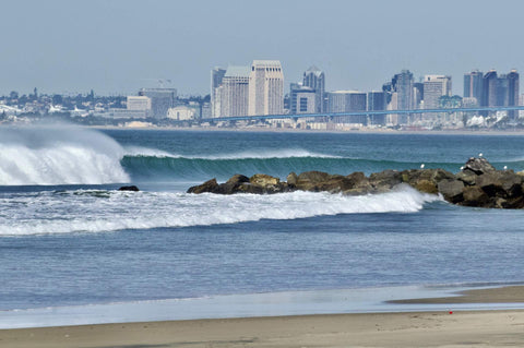 City skyline with waves crashing against rocks on a beach.  Shot in San Diego, California. © Randy Dible Photo