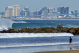 Person walking on a beach with waves and city skyline in the background.  Shot in San Diego, California. © Randy Dible Photo