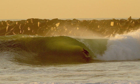 Surfer riding a wave in the ocean with a sunset or sunrise sky. Shot in San Diego, California. © Randy Dible Photo